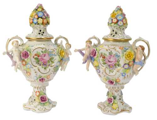 A pair of Schierholz porcelain twin handled vases, each with a floral encrusted and pierced lid, each handle decorated with an applied putto to each side, the main body with handpainted and floral encrusted decoration, gilt heightened, printed marks, 33cm