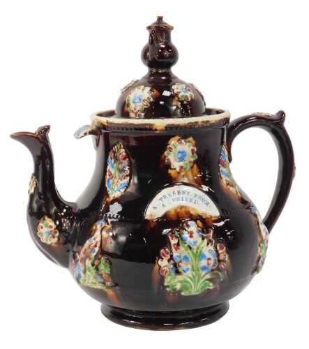A 19thC treacle glaze Bargeware teapot, with teapot finial to lid, decorated in relief with flowers, birds, etc., and bearing plaque A Present from a Friend, 35cm high. (AF)