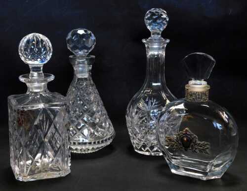 A group of decanters, comprising square cut glass decanter and stopper, 26cm high, cut glass bottle shaped decanter, 30cm high, decanter and stopper of cylindrical tapering form, 26cm high, and another with white metal mounts, 24cm high. (4)