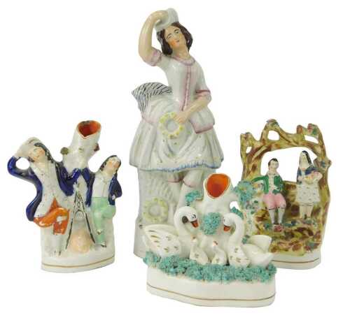 A group of 19thC Staffordshire pottery, comprising lady dancing, 30cm high, spill vase depicting swans and cygnets, 12cm high, a further spill vase depicting two gentlemen dancing, 18cm high, and a flat back group depicting male and female holding flowers