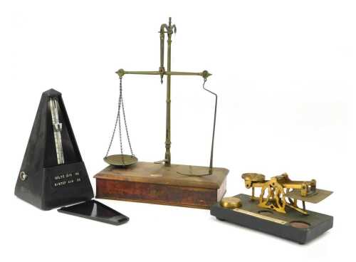 A set of 19thC brass postage scales, on an ebonised base, bearing plaque, with one weight, 20cm wide, together with Jaccard metronome, and a pair of Victorian brass scales, on a mahogany base, lacking one brass tray, 38cm high.