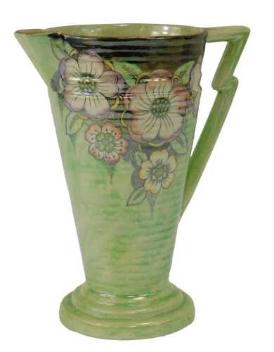A Kensington Ware Art Deco style pottery jug, of conical ribbed form, decorated with flowers, against a pale green ground, gilt heightened, printed marks, 23cm high.