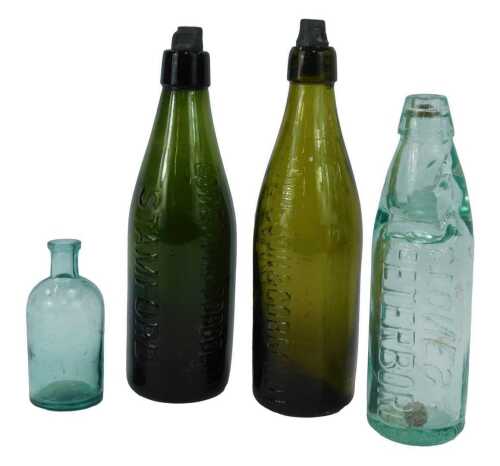 A group of green glass bottles, comprising two Lowe Son and Coppold Ltd Stamford, each with stoppers, the largest 27.5cm high, another for Stones Peterborough, and one unmarked.