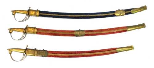 Three reproduction Indian sabres, each with a decorative metal blade, lion head hilt and pierced hand guard, in velvet and brass scabbards, two in red and one in blue, each 88cm long overall.