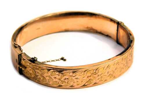 A 9ct gold hinged bangle, the half hoop design with floral scroll decoration with leaf and vine, 12.4g all in, boxed. (AF)