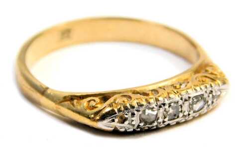 A diamond gypsy ring, set with five tiny diamonds, in a white gold claw setting, with scroll design shoulders, on a yellow metal band stamped 9ct, ring size O&frac12;, 3g all in.