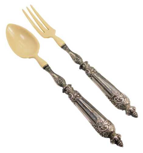 A pair of Continental faux ivory salad servers, with white metal handles embossed with flowers and foliate scrolls.