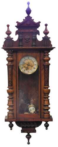 A 20thC walnut cased Vienna wall clock, the circular dial bearing Roman numerals, with embossed floral decoration, eight day movement, with key and pendulum, 103cm high.