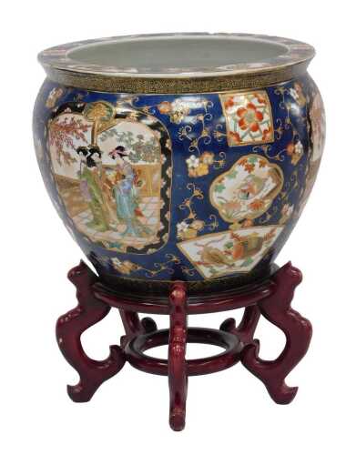 A 20thC Oriental porcelain jardiniere, decorated with reserves depicting geisha, in an interior setting surrounded by floral decoration against a dark blue ground, 36cm high, 42.5cm diameter, together with a hardwood stand.