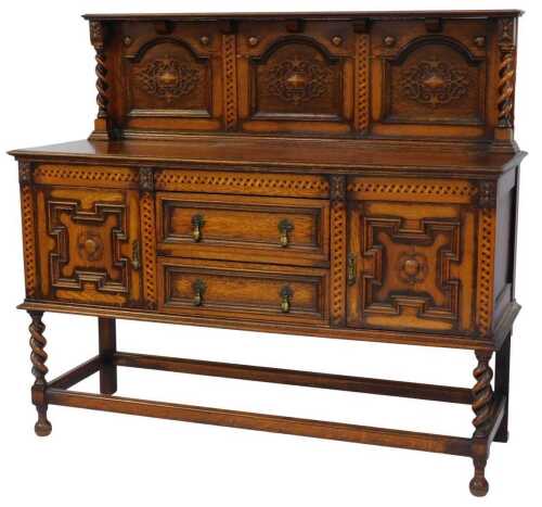 An early 20thC oak sideboard, the top with a raised carved back, on spiral turned supports, the base with two drawers flanked by two panelled cupboards, on spiral turned legs united by stretchers, on turned cylindrical feet, 137cm high, 151cm wide, 56cm d