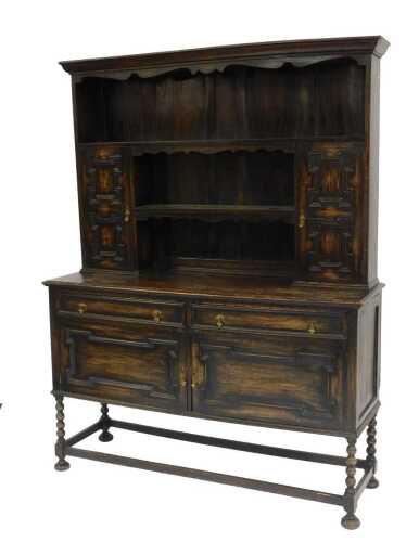 A 20thC oak dresser, the top with a moulded edge above one long shelf and two shorted shelves flanked by two panelled cupboards, the base with two drawers above two panelled cupboards, on bobbin turned legs united by stretchers, 200cm high, 154cm wide, 47