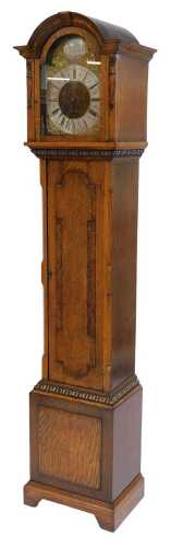 An early 20thC oak cased longcase clock, the brass break arch dial with silvered chapter ring, bearing Roman numerals, below a Tempus Fugit circular plaque, the face decorated with cherub and scrolling spandrels, the hood carved with foliate and leaf moti