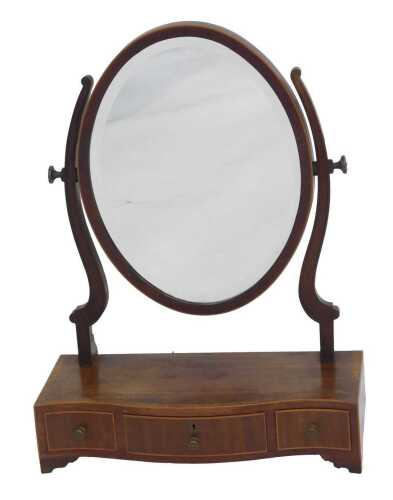 A Victorian mahogany and cross banded swing frame mirror, the oval mirror on scrolling supports, on a serpentine fronted base, with one long and two short drawers, on bracket feet, 61cm high, 48cm wide, 21cm deep.
