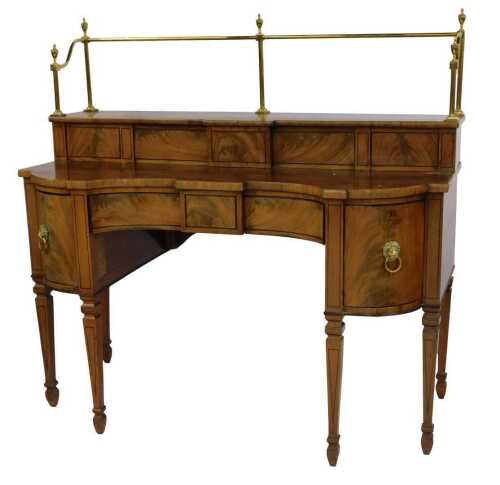 A George IV flame mahogany and ebony line inlaid inverted serpentine sideboard, with brass rail back surmounted by urn finials, with upper shelf with two sliding doors, the base with central door flanked by two cupboards with brass lion mask ring handles,