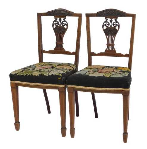 A pair of Victorian mahogany and boxwood line inlay salon chairs, each with a carved rail, pierced urn shaped splat with floral embroidered overstuffed seats, on square tapering legs and spade feet.