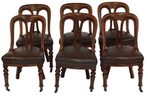 A set of six 19thC mahogany dining chairs, each with a curved pierced back with scrolling decoration, on a brown leather upholstered seat, on turned and fluted legs with castors.