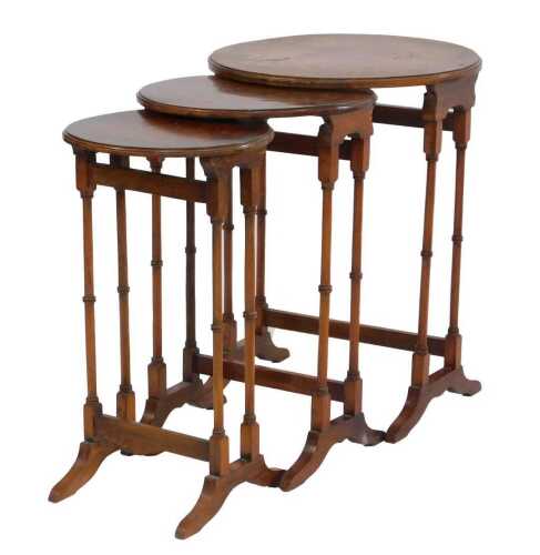 A 20thC walnut nest of three tables, each with a circular burr walnut top, on turned legs, with stretcher, on out splayed feet, the largest 60cm high.
