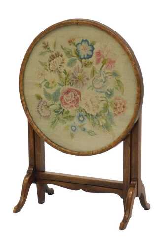 An early 20thC mahogany folding table, the circular glazed top inset with a floral embroidered panel, on out splayed legs, united by an X frame stretcher, 48cm high, the top 48cm diameter.