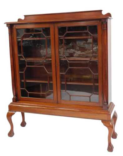 A Victorian display cabinet, the top with a raised back, the front with two astragal glazed doors with columns to either side, enclosing four shelves, on a moulded base, on cabriole feet, on ball and claw feet, 168cm high, 137cm wide, 40cm deep.