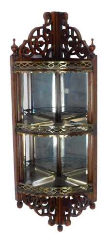 An Edwardian mahogany corner display shelf, the raised pierced back with urn finials, above a pierced brass shelf, above two further shelves with mirrored backs, with a pierced section to the base, bearing label verso for MW Edgley and Co Looking Glass Ma