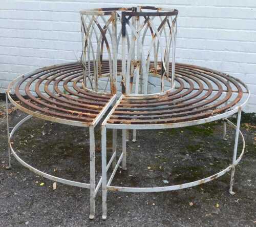 A wrought iron and cream painted garden tree bench, splitting in two sections, the centre 54cm diameter. (AF)