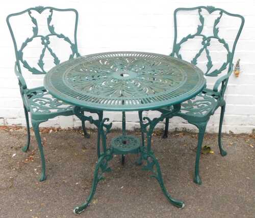 A cast metal circular green garden table, pierced round top, 72cm high, 80cm wide, and two chairs.