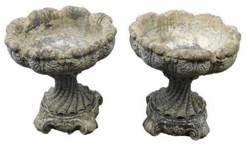 A pair of reconstituted stone shell shaped planters, each on a stepped foot, 48cm high, 44cm wide.