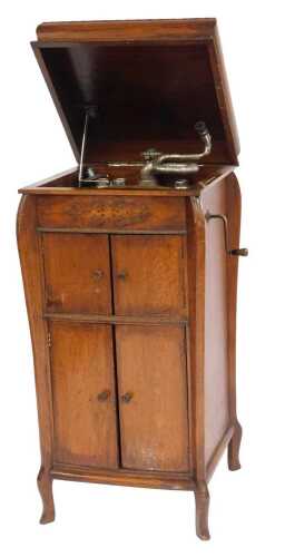 An early 20thC oak cased gramophone, the hinged lid containing a Gilbert's turntable, the base with two pairs of cupboard doors, on squat cabriole legs, 108cm high, 50cm wide, 50cm deep.