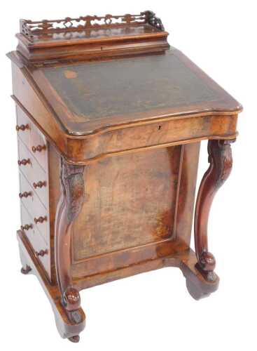 A Victorian walnut Davenport, the pierced galleried top enclosing an arrangement of recesses, the fall with a green gilt tooled leather inset enclosing three drawers, the base with four drawers to one side and dummy drawers to the other, on scrolling carv