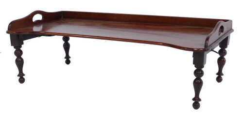 A Victorian mahogany two handled bed tray,&nbsp;by Carter's of London, No 25296, bearing label, the shaped top with a raised back, on turned tapering stained beech legs,&nbsp;22cm high, 68cm wide, 36cm deep.