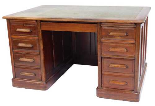 An early 20thC walnut pedestal desk, the top with a rounded edge inset with a green gilt tooled leather inset, the base with a central drawer flanked by four drawers to each side, on plinth base, 77cm high, 135cm wide, 89cm deep.