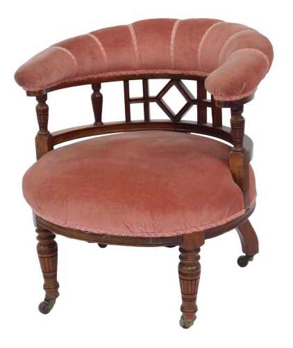 A Victorian walnut tub chair, the overstuffed back in pink upholstery, above a pierced section supported by columns, pink overstuffed seat, on turned cylindrical carved legs, 64cm high.