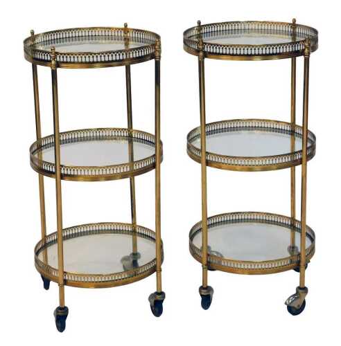 A pair of 20thC brass three tier trolleys, each with a pierced border, on castors, 65cm high, 30cm diameter.