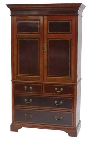 A late 19th/early 20thC mahogany and satinwood cross banded linen press, the top with a moulded edge above two panelled doors enclosing an arrangement of drawers, the base with two short and two long drawers, on bracket feet, 200cm high, 113cm wide, 52cm 
