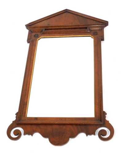A mahogany wall mirror, the triangular top above a shaped mirror plate with two roundels, on a scrolling and shaped base, 104cm high, 57cm wide.