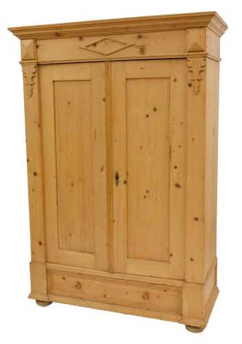 A 20thC pine double wardrobe, the top with a moulded cornice above two panelled doors with drawer to base, on bracket feet, 190cm high, 128cm wide, 52cm deep.