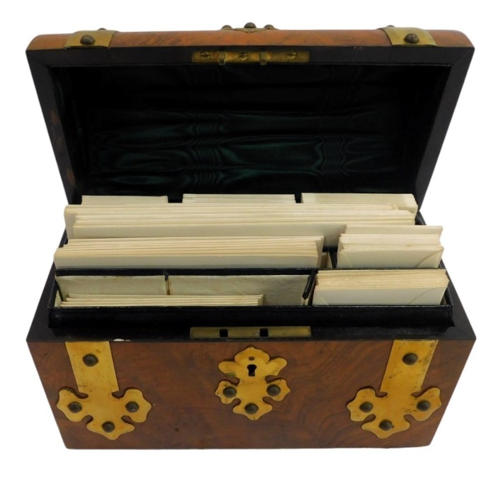 A Victorian walnut and brass bound stationary box, with a domed top, enclosing various recesses for writing paper and envelopes, 22.5cm wide.