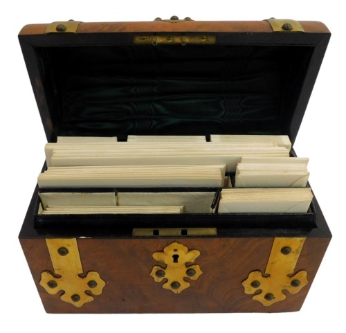 A Victorian walnut and brass bound stationary box, with a domed top, enclosing various recesses for writing paper and envelopes, 22.5cm wide.