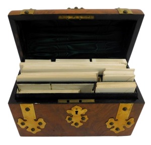 A Victorian walnut and brass bound stationary box, with a domed top, enclosing various recesses for writing paper and envelopes, 22.5cm wide.
