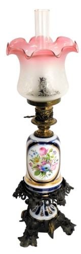 A Victorian oil lamp, with a pink and frosted etched glass shade, a porcelain central reservoir decorated with flowers, on a leaf decorated cast metal and porcelain base, with chimney, approx 66cm high overall.