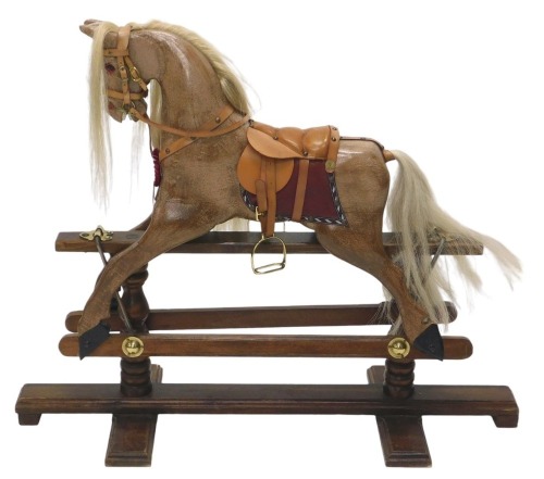 A 20thC rocking horse, the brown wooden painted horse on oak base, with red and brown leatherette saddle with rosette, 86cm high, 106cm wide, 41cm deep.