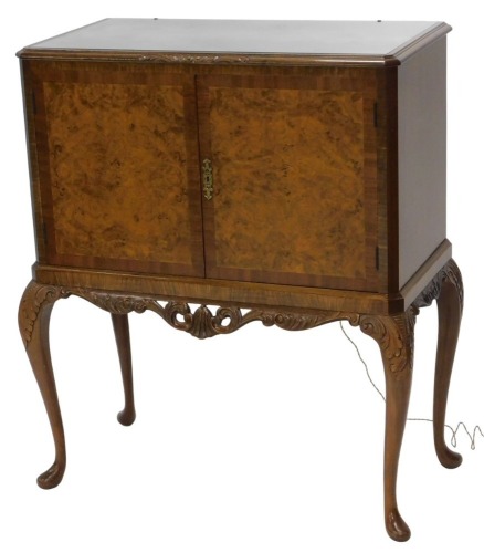 A reproduction figured walnut cocktail cabinet, with plate glass top and fitted interior enclosed by two doors with burr walnut veneer, with carved scroll apron below and carved cabriole legs, 109cm high, 95cm wide, 45cm deep.&nbsp;WARNING! This lot contains u