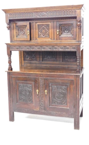 An 18thC and later Welsh oak tridarn, moulded cornice and canopy top, with gouged frieze and carved decoration, cupboards below with recess panelled doors and centre carved panel, lower tier and base, the stepped lower tier having carved frieze and turned