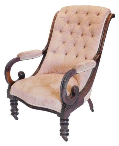 A mahogany framed button back upholstered arm chair, with high scrolling back, and open scroll arms, with padded rests, upholstered in pink damask material, raised on low turned legs with brass castors.