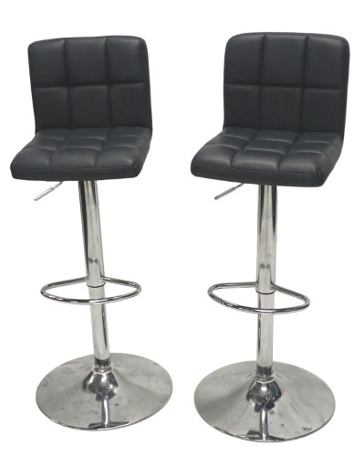 A pair of modern breakfast bar stools, with padded vinyl seats and low backs, adjustable seats, tubular columns, circular tapered feet.