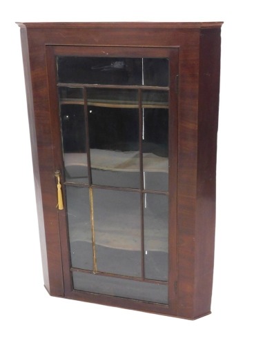 A 19thC mahogany glazed hanging corner wall cabinet, with canted sides and single glazed door, enclosing three shaped shelves, 77cm wide.