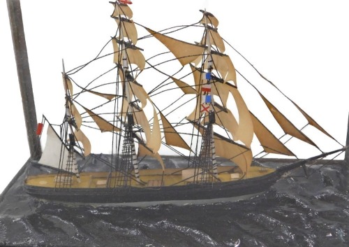A 20thC ship model diorama, the three masted ship, in rough seas, in a walnut display case, 12cm high, 18cm wide, 9cm deep.