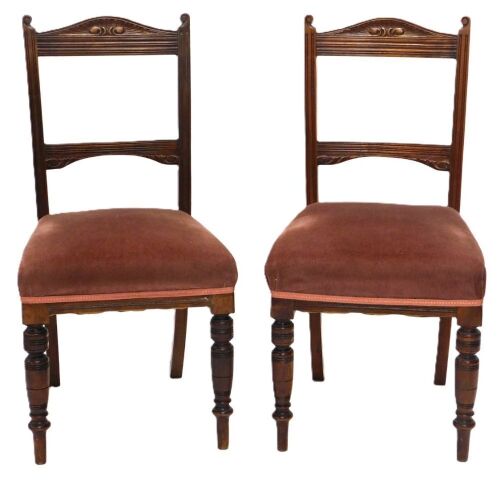 A pair of Edwardian walnut dining chairs, with carved cresting rails, and over upholstered seats.