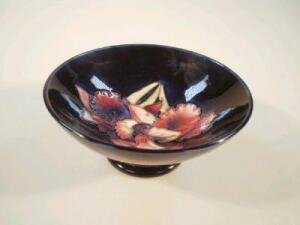 A Moorcroft bowl decorated with clematis designs on a blue ground and circular