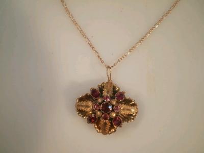 A garnet set floral pendant in yellow metal to yellow metal chain